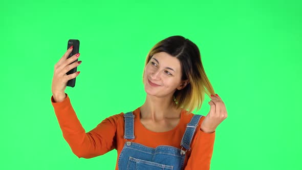 Young Woman Makes Selfie on Mobile Phone Then Looking Photos on Green Screen