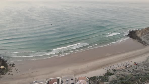 Long waves washing in at calm beach in Burgau, Portugal