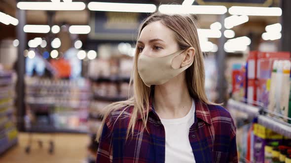 Woman in Protective Mask Walking By Supermarket Between Aisles Looking for Something