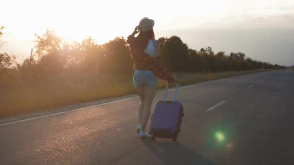 Young Woman with a Suitcase on Road. Funny Beautiful Girl Traveler. Travel Concept Video.