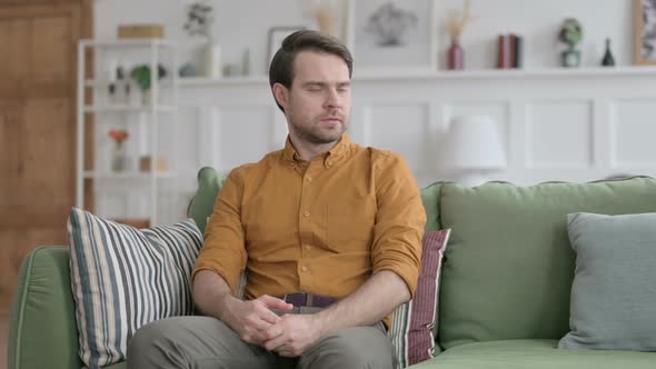Young Man Feeling Worried while Sitting on Sofa