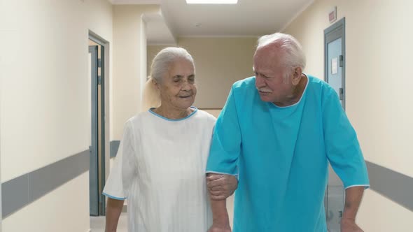 Old woman going through hospital hallway near old man