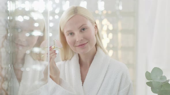 Pretty Female Doing Facial Massage in Bright Bathroom