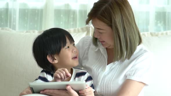 Asian Child And His Mother Using Tablet Together