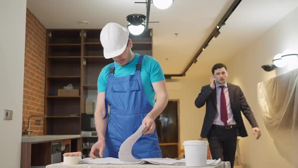 Positive Builder in Hard Hat Welcoming Owner in New Flat Indoors