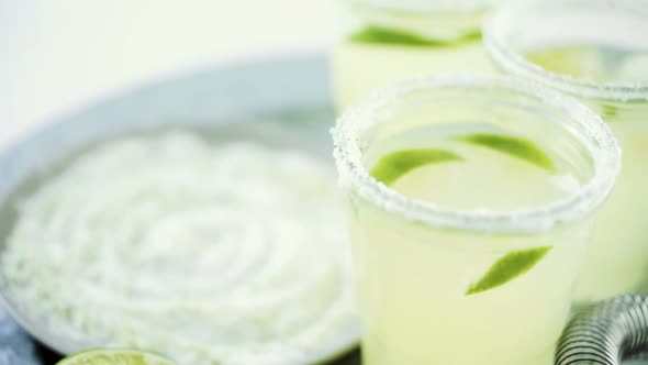 Key lime margarita garnished with fresh lime and salt in mason jar on metal tray.