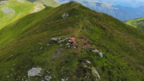 Aerial: couple backpackers hiking on mountain top Summer adventures on the Alps