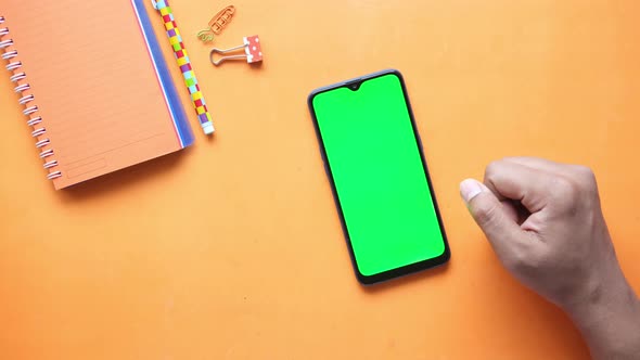 Young Man Hand Scrolling Smart Phone on Orange Background