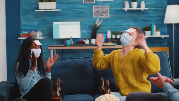 Group of Friends with Protective Masks Playing Who Am I Game