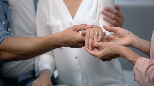 Man Holding Fiancee Hand With Engagement Ring, Showing to Mother, Happy Family