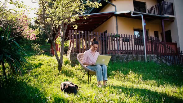 A Young Adult Woman Working on Her Laptop While Sitting in the Garden