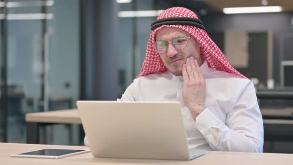 Middle Aged Arab Man with Laptop having Toothache, Cavity