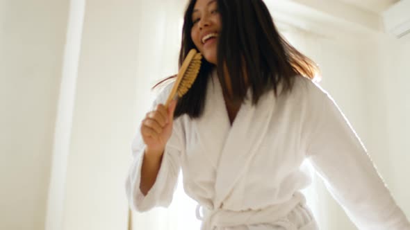 Webcam Pov Portrait of Young Optimistic Asian Lady Singing to Camera with Hair Brush Posing Against