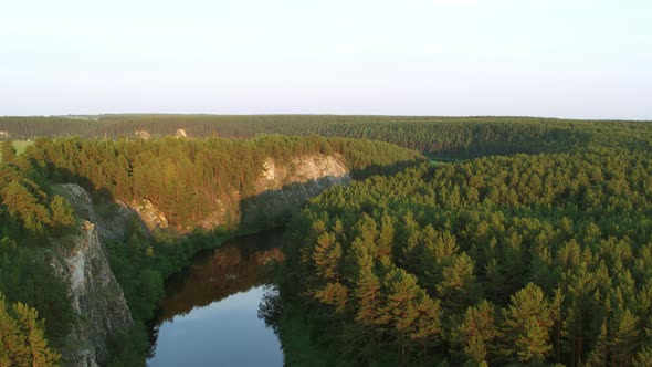 Aerial View of the River with a Rock and Forest on the Banks