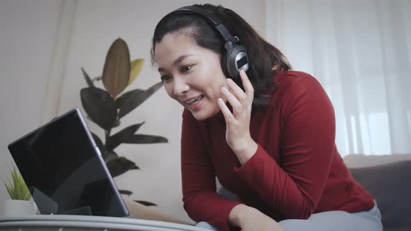 Freelance woman redshirt using tablet with headphone for meeting online at home