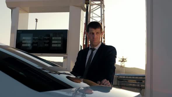 Successful man in a jacket refuel his car at a gas station