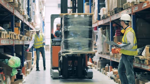 Warehouse Worker on a Forklift Getting Up Goods To Upper Shelf