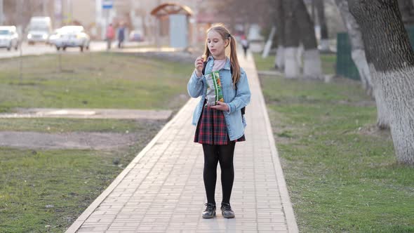 Young School Girl Eating Chips From Packet on Street