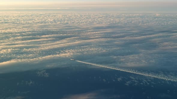 Incredible view from the cockpit of an airplane flying high above the clouds leaving a long white co