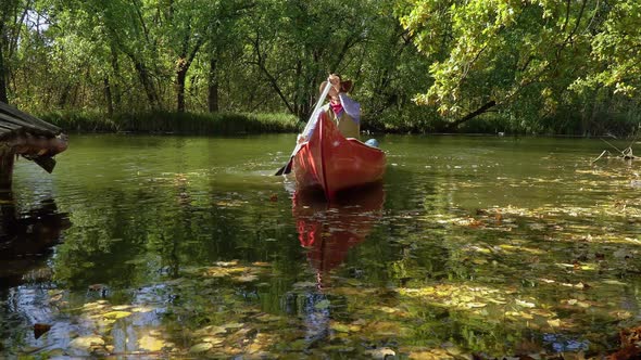 Cowboy in a Canoe Floats on the River in the Forest