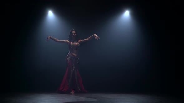 Girl Starts Dancing Belly Dance with Red Dress . Black Smoke Background