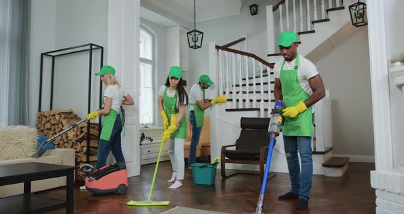 Professional Multiracial Team of Cleaners Cleaning Up Client's Beautiful Apartment