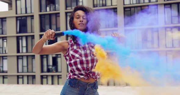 Fashionable young woman on urban rooftop using smoke grenades