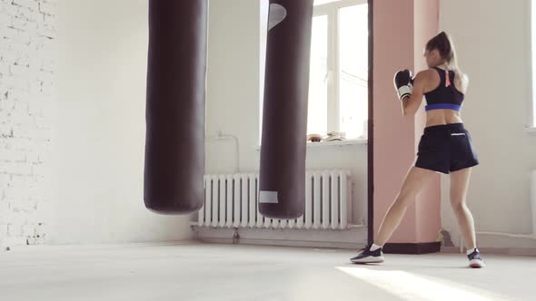 Female Athlete Boxing the Punching Bag in Urban Industrial Gym