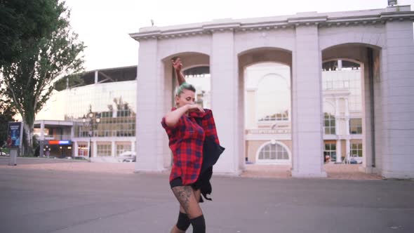 Young Stylish Funky Girl with Green Hair Riding Roller Skates and Dancing in Park Slow Motion