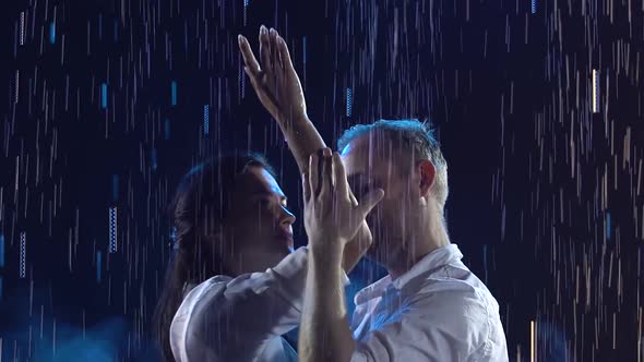 Cute Smiling Couple Dancing Salsa in a Dark Studio. A Man and a Woman in White Clothes Are Enjoying