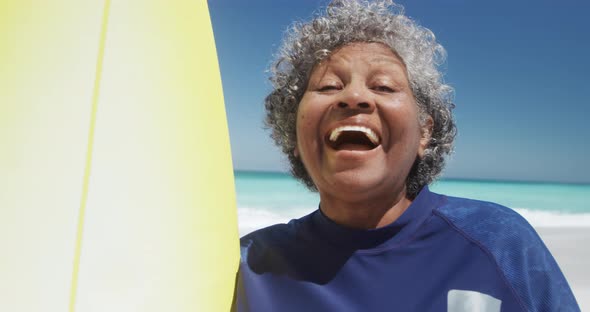 Senior woman with a surfboard smiling