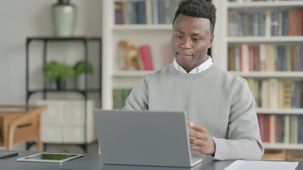 African Man Talking on Video Call on Laptop in Library