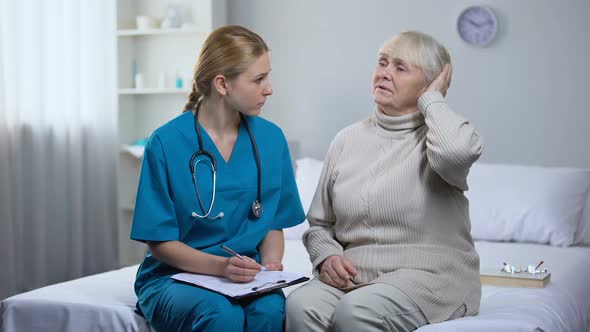 Aged Woman Complaining Doctor on Head Ache, Therapist Writing Medical Records