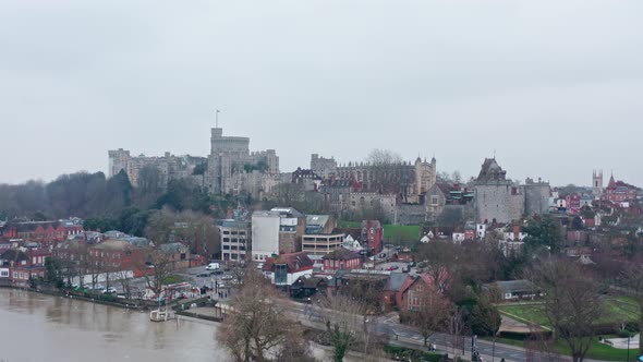 Rising aerial drone shot of Windsor castle from Eton on a cloudy day