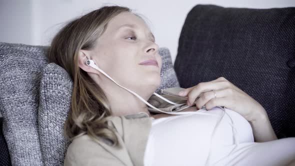 Relaxed Pregnant Woman Listening To Music on Sofa