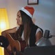 Beautiful Black Woman in Santa Hat Singing and Playing Guitar on Christmas Eve - VideoHive Item for Sale