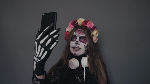 Girl in Halloween Makeup Santa Muerte or Sugar Mexican Skull Posing in the Phone Makes a Selfie