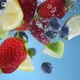 Super slow motion shot of fruit falling into the water with splashing. Blue background. - VideoHive Item for Sale