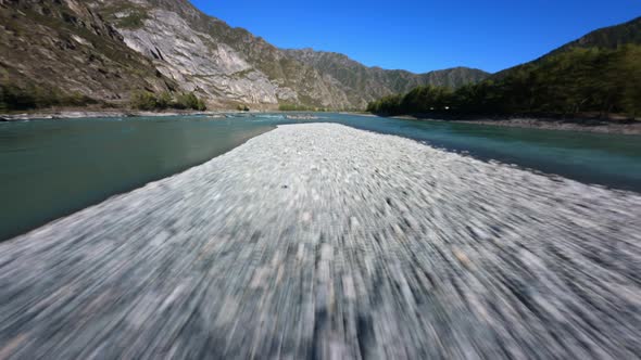 FPV Sports Drone Speed Flight Mountain River Calm Water Surface with Stones at Cliff Natural Valley