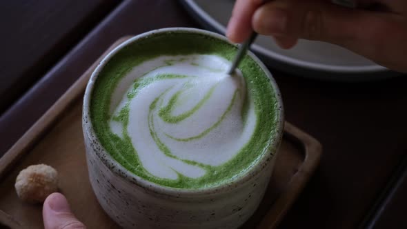 Mixing Foam of Hot Japanese Green Tea Matcha Latte Healthy Detox and Aromatic Beverage in Restaurant