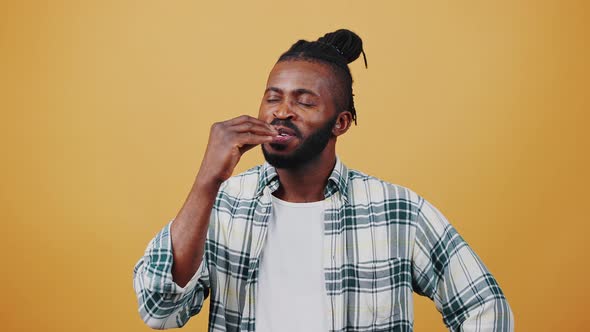 Young Afro American Guy Smiling Showing Tasty or Delicious Hand Gesture By Kissing His Fingers