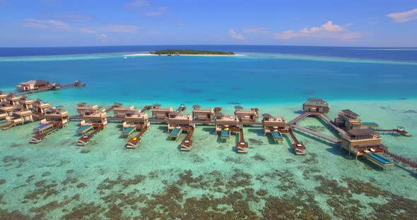 Aerial drone view of scenic tropical island and resort hotel with overwater bungalows in Maldives