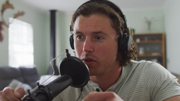 Focused caucasian man wearing headphones, talking and recording