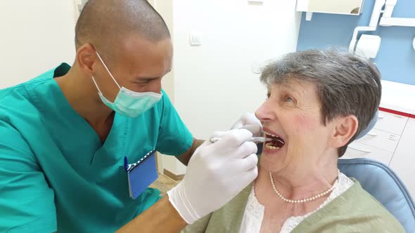 Close up of dental assistant examining elderly female patient