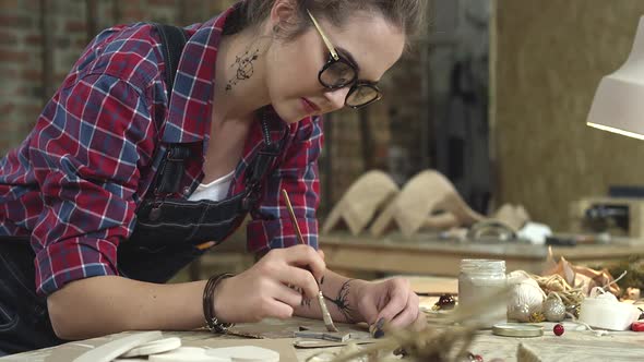 Young Hipster Painting Handmade Goods in her Studio