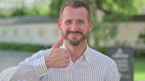Outdoor Portrait of Middle Aged Man Showing Thumbs Up Sign
