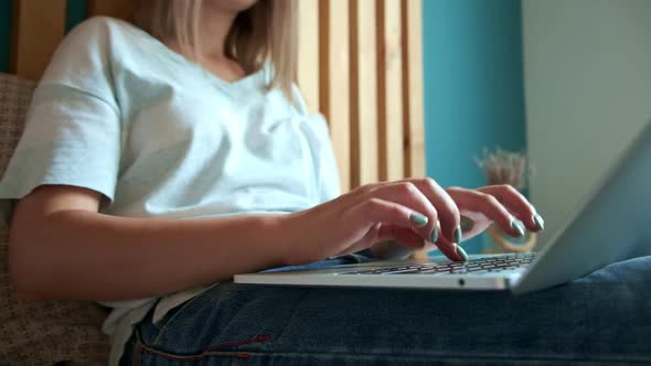 Young Woman Quickly Typing on the Keyboard Using Laptop to Work Lying on the Bed in the Bedroom