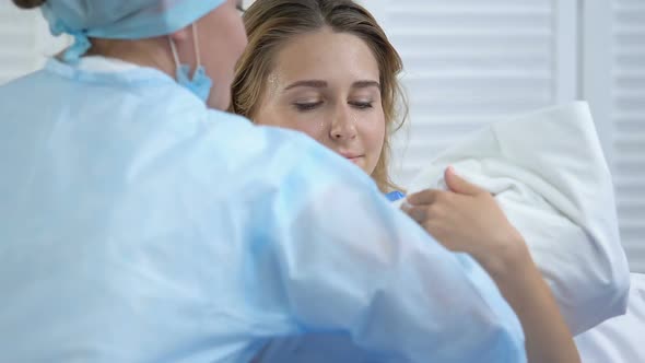 Labor Nurse Giving Newborn Baby to Sweaty Young Mother, Maternity, Childbirth