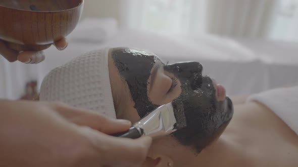 Young beautiful woman makes charcoal spa therapy