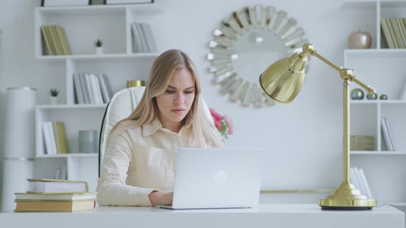 Unhappy young girl at work in the office. Serious woman typing on laptop at home